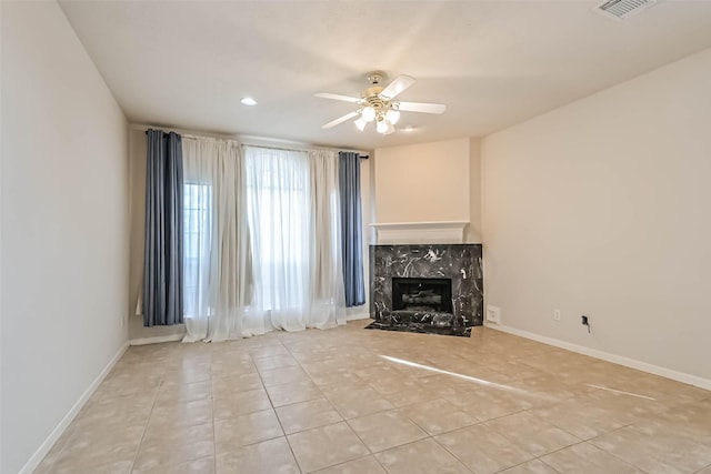 unfurnished living room featuring ceiling fan, light tile patterned flooring, and a high end fireplace