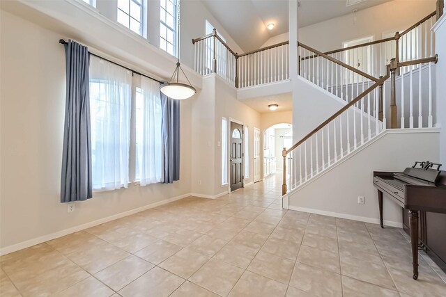 1408 S Friendswood Dr Unit 101, Friendswood, TX 77546 - entryway featuring light tile patterned flooring, arched walkways, stairs, high vaulted ceiling, and baseboards