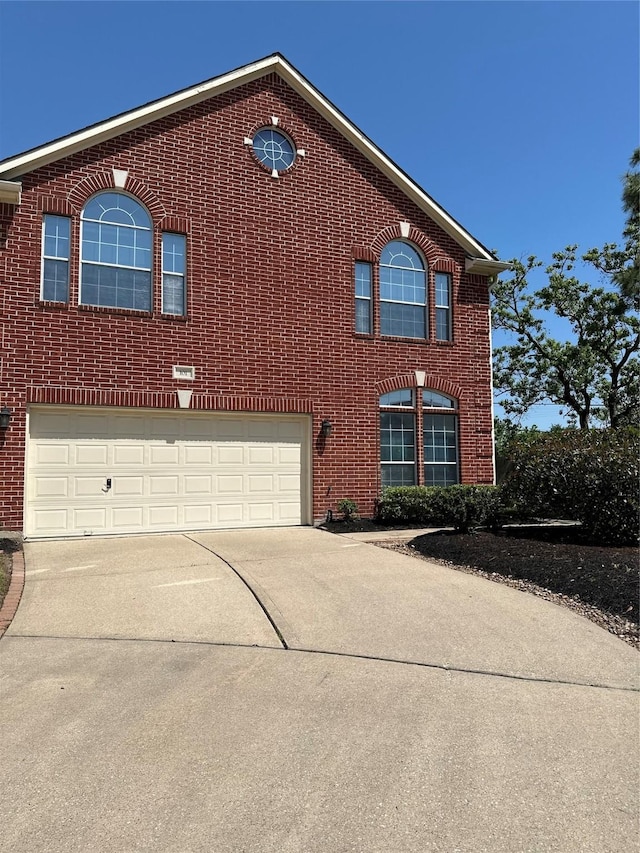 view of front of home with driveway, a garage, and brick siding