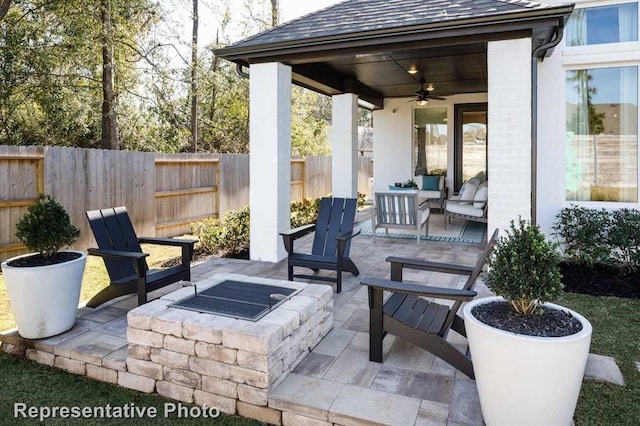 view of patio / terrace with a fenced backyard, an outdoor living space with a fire pit, and ceiling fan