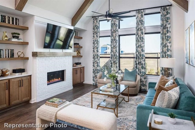 living room featuring a glass covered fireplace, baseboards, a ceiling fan, dark wood finished floors, and vaulted ceiling with beams