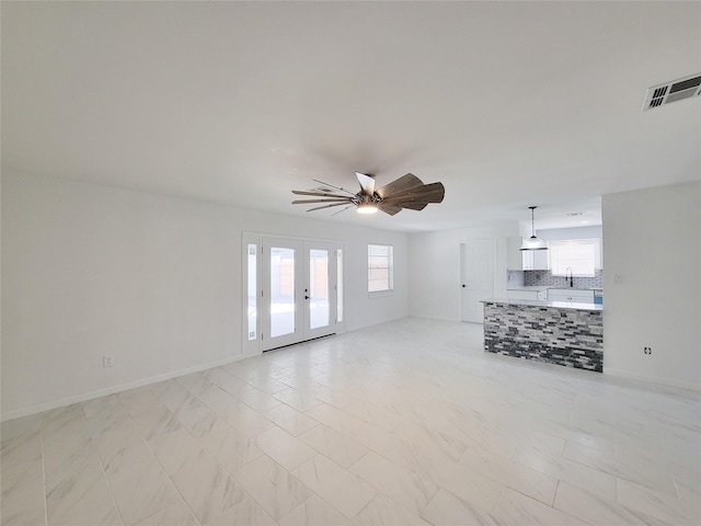 unfurnished living room featuring ceiling fan and french doors