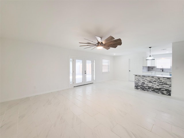 unfurnished living room featuring ceiling fan and french doors