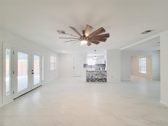 unfurnished living room featuring french doors and ceiling fan