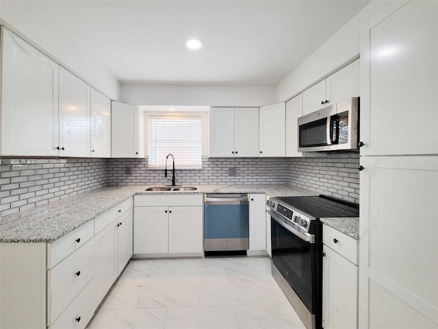 kitchen featuring stainless steel appliances, sink, white cabinets, and backsplash