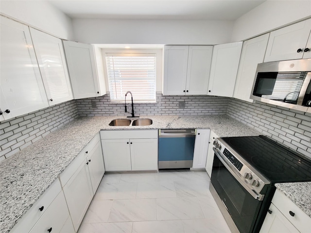 kitchen featuring appliances with stainless steel finishes, tasteful backsplash, white cabinetry, sink, and light stone counters