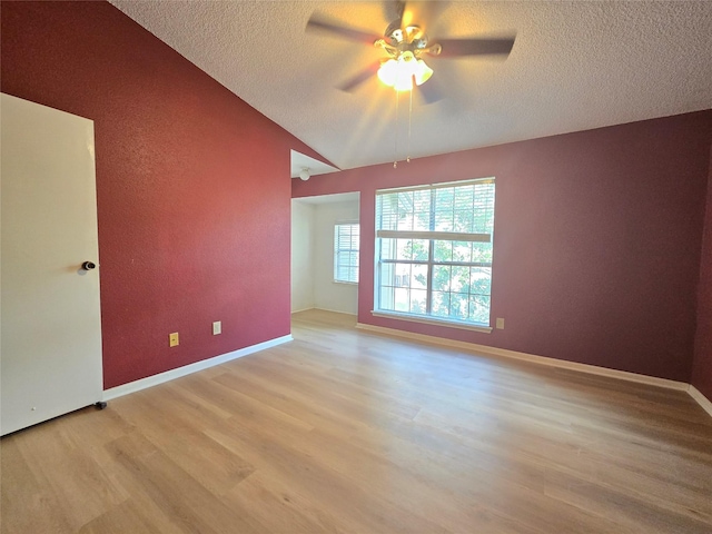 spare room featuring lofted ceiling, ceiling fan, light hardwood / wood-style flooring, and a textured ceiling