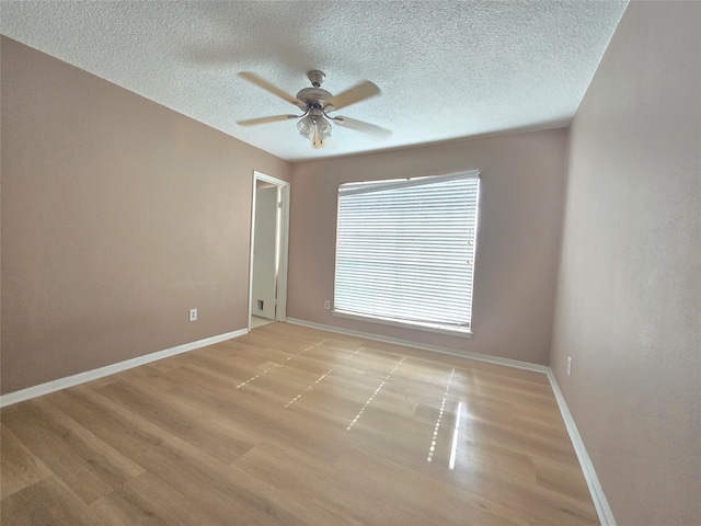 empty room with ceiling fan, light hardwood / wood-style floors, and a textured ceiling