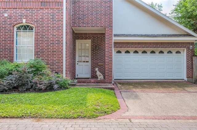 property entrance with driveway, brick siding, an attached garage, and stucco siding