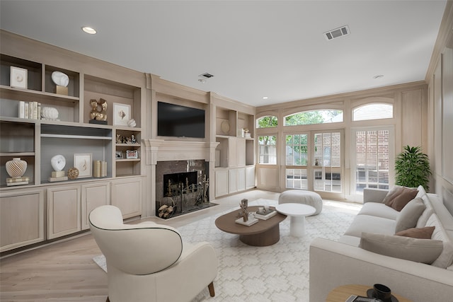 living room with light hardwood / wood-style flooring, a fireplace, and built in shelves