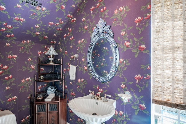 bathroom with a sink and wallpapered walls