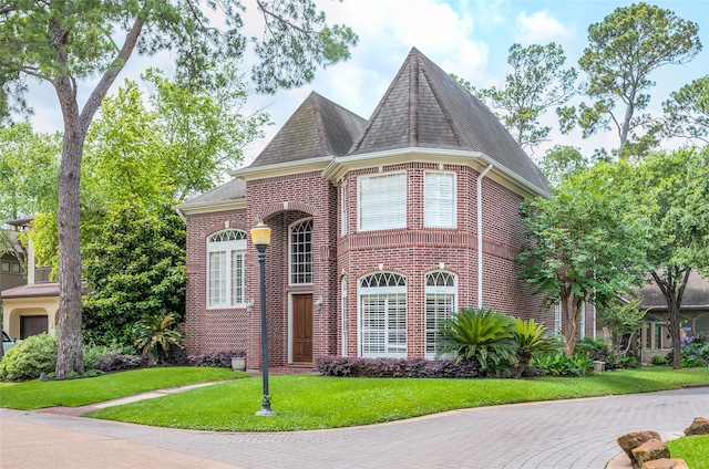 view of front of house with roof with shingles, a front lawn, and brick siding