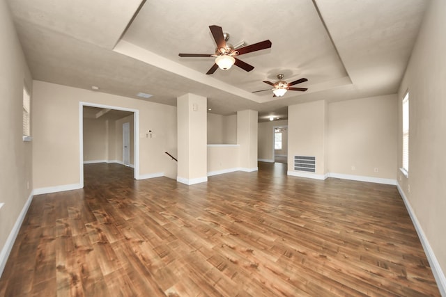 unfurnished living room featuring a raised ceiling and wood-type flooring