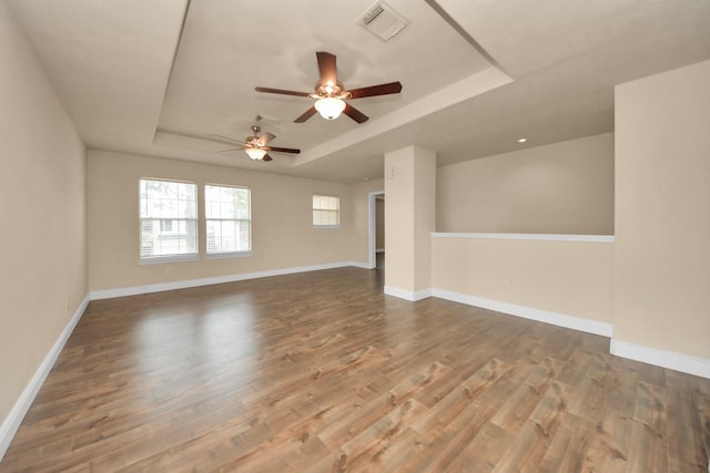 unfurnished living room with ceiling fan, wood-type flooring, and a raised ceiling