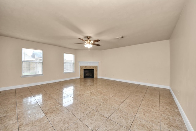 unfurnished living room with a tile fireplace, light tile patterned floors, and ceiling fan