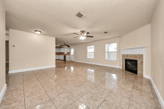 unfurnished living room featuring ceiling fan, a fireplace, and light tile patterned floors