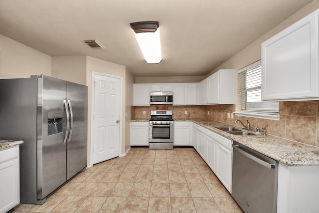 kitchen with sink, tasteful backsplash, light stone counters, stainless steel appliances, and white cabinets