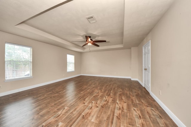 empty room featuring a raised ceiling, dark hardwood / wood-style floors, and ceiling fan