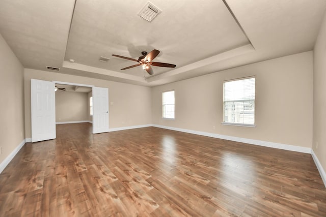 spare room with ceiling fan, a tray ceiling, and hardwood / wood-style floors