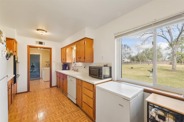 kitchen featuring washer / clothes dryer, sink, light parquet floors, fridge, and white dishwasher