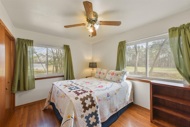 bedroom with multiple windows, wood-type flooring, and ceiling fan