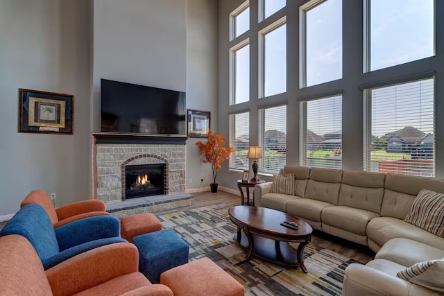 living room with hardwood / wood-style flooring, a fireplace, and a towering ceiling