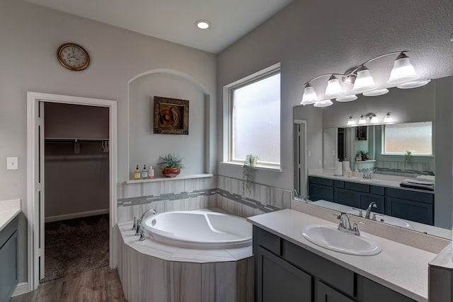 bathroom featuring vanity, tiled tub, and hardwood / wood-style flooring