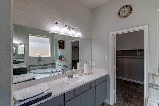 bathroom featuring an inviting chandelier, vanity, and a bathing tub