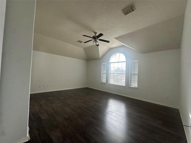 additional living space with a textured ceiling, vaulted ceiling, dark hardwood / wood-style floors, and ceiling fan