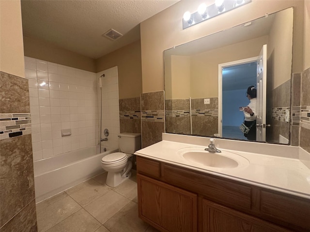 full bathroom with tile walls, tile patterned flooring, vanity, a textured ceiling, and tiled shower / bath