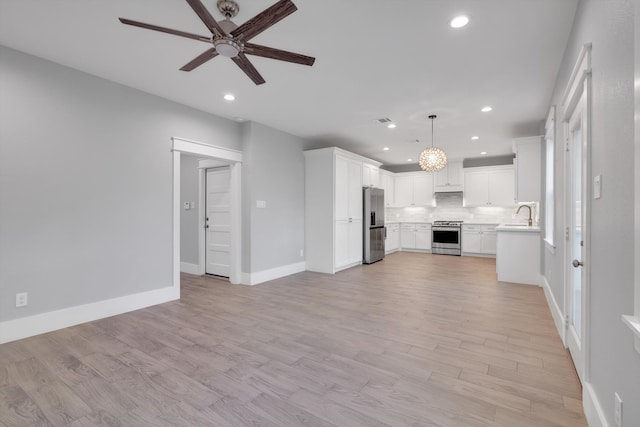 unfurnished living room with sink, ceiling fan, and light hardwood / wood-style flooring