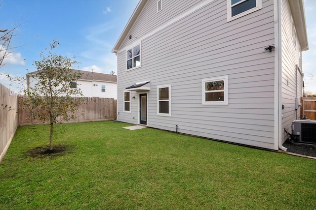 back of property featuring central AC unit and a lawn