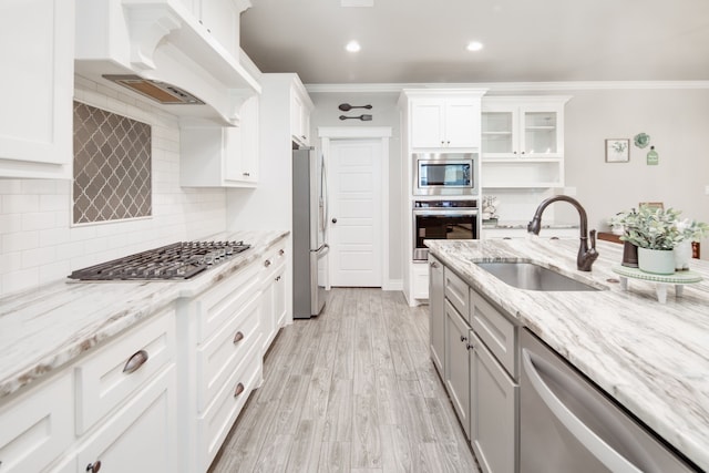 kitchen with premium range hood, sink, appliances with stainless steel finishes, light stone countertops, and white cabinets