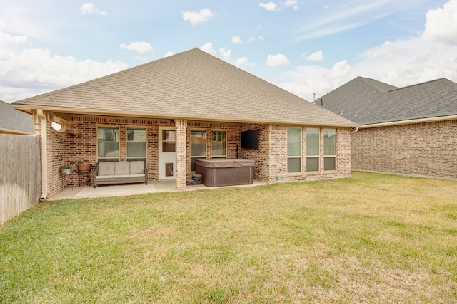 rear view of property with a hot tub, a patio area, and a lawn