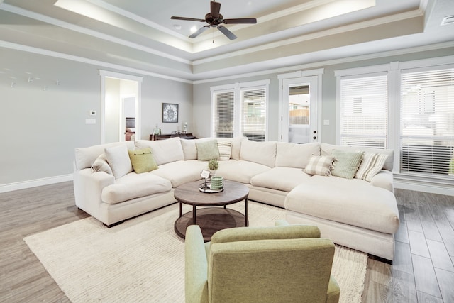 living room featuring ceiling fan, ornamental molding, wood-type flooring, and a tray ceiling