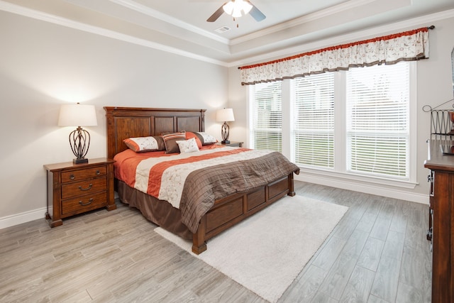 bedroom with a raised ceiling, ornamental molding, ceiling fan, and light hardwood / wood-style floors