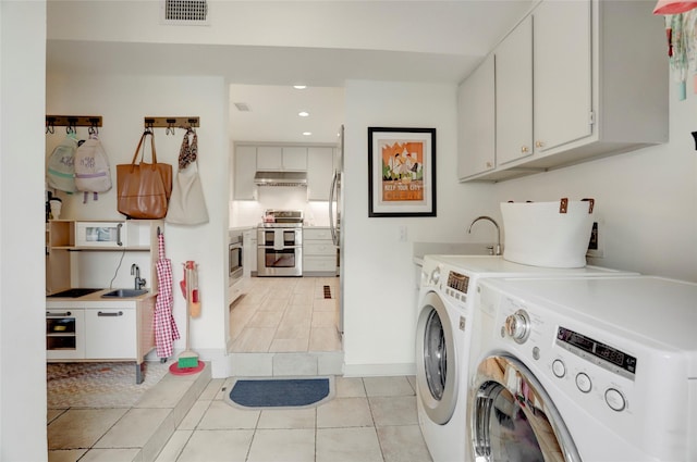 washroom featuring separate washer and dryer, sink, cabinets, and light tile patterned flooring