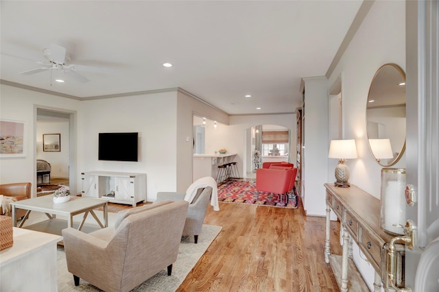 living room featuring ornamental molding, ceiling fan, and light wood-type flooring