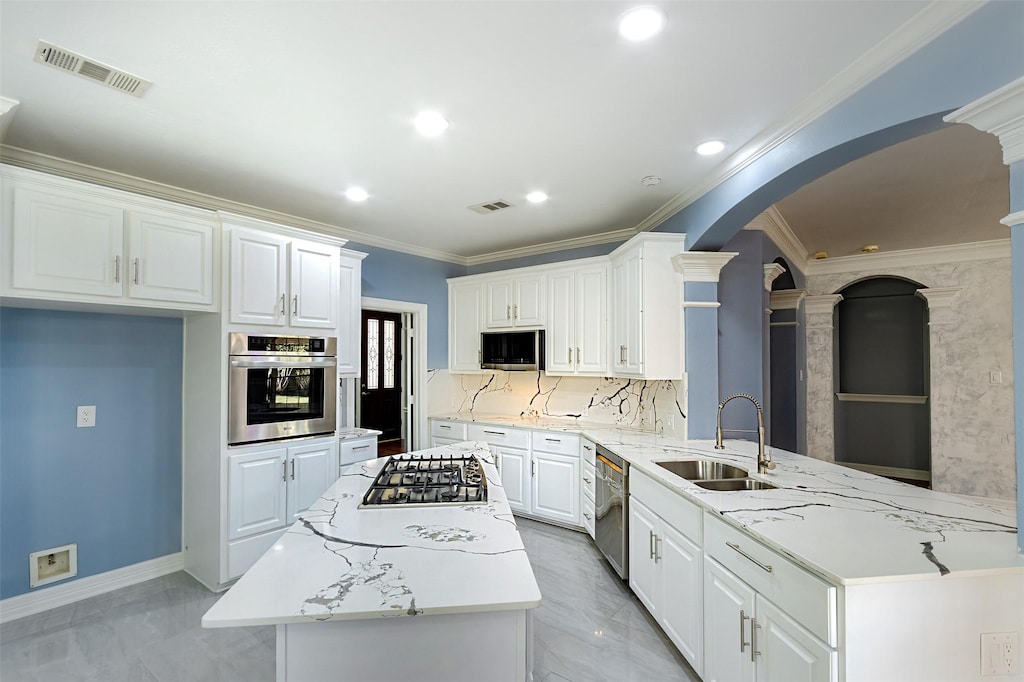 kitchen featuring sink, appliances with stainless steel finishes, white cabinetry, light stone counters, and kitchen peninsula