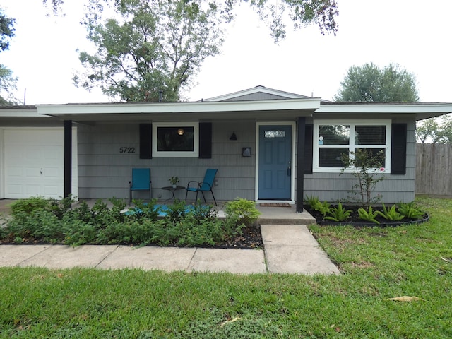 ranch-style home featuring a garage, covered porch, and a front lawn