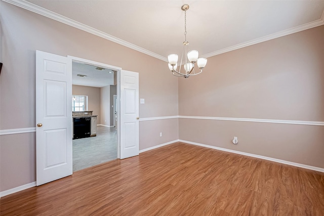 empty room featuring an inviting chandelier, hardwood / wood-style floors, and ornamental molding