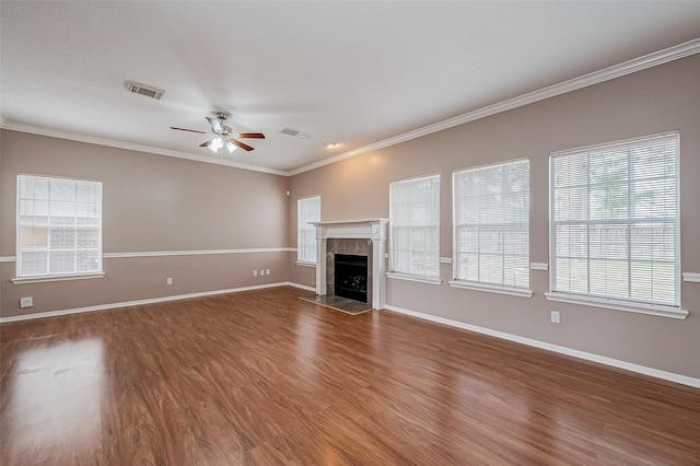 unfurnished living room featuring a tiled fireplace, ornamental molding, dark hardwood / wood-style floors, and ceiling fan