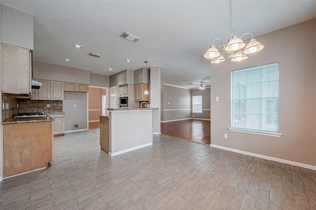 kitchen with light stone counters, decorative light fixtures, ceiling fan with notable chandelier, light hardwood / wood-style floors, and decorative backsplash