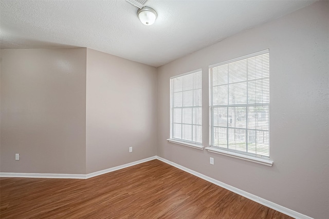 empty room with hardwood / wood-style flooring and a textured ceiling