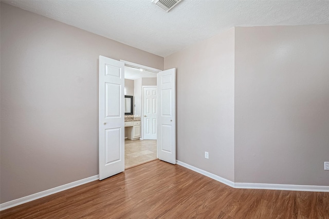 spare room featuring light hardwood / wood-style flooring and a textured ceiling