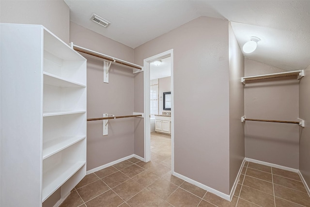 spacious closet with vaulted ceiling and tile patterned floors