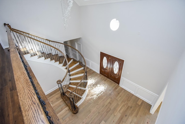 foyer entrance featuring hardwood / wood-style flooring, crown molding, and a high ceiling