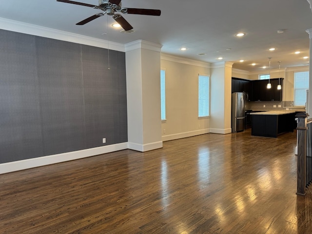 unfurnished living room with ceiling fan, crown molding, dark wood-type flooring, and a wealth of natural light