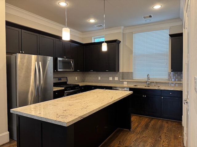 kitchen featuring sink, a center island, hanging light fixtures, stainless steel appliances, and light stone countertops