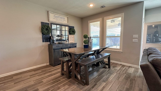 dining space featuring dark wood-type flooring and a textured ceiling